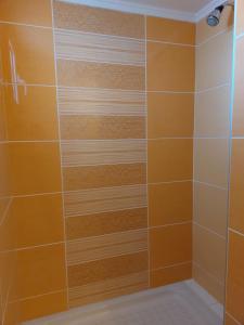 ducha con azulejos de color naranja y blanco en Nefeli Seaside Apartments, en Polychrono
