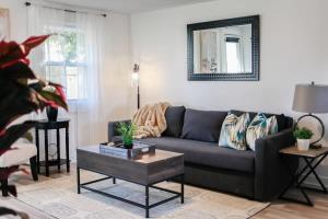 a living room with a gray couch and a mirror at Sojourn Beachside Hideaway 2 BR in Norfolk