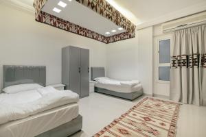 a bedroom with two beds and a rug at Sands Inn Hostel in Riyadh