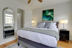 ein weißes Schlafzimmer mit einem großen Bett und einem Spiegel in der Unterkunft Sojourn Townhome in Old Town Alexandria with Relaxing Yard in Alexandria