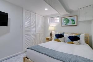 ein Schlafzimmer mit einem weißen Bett mit Kissen und einem TV in der Unterkunft Sojourn Townhome in Old Town Alexandria with Relaxing Yard in Alexandria + 16 Fotos