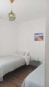 a white bedroom with two beds and a lamp at Casa en Calle del Agua in Vega de San Mateo