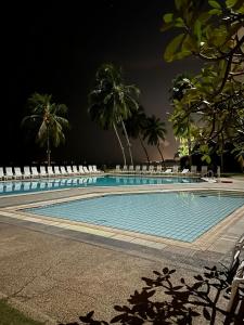 a swimming pool with chairs and palm trees at night at Seaview Retreat -Regency Tg Tuan Beach Resort, Port Dickson, Malaysia in Port Dickson
