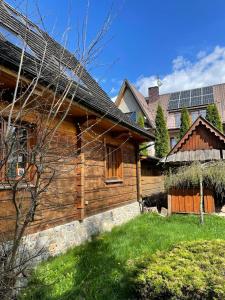 Villa Pandora - Zakopane Centrum في زاكوباني: منزل خشبي على السطح مع لوحات شمسية
