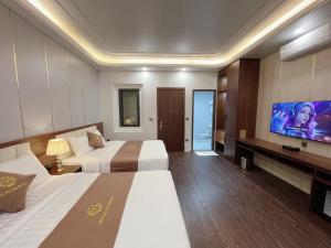 ein Hotelzimmer mit 2 Betten und einem Flachbild-TV in der Unterkunft HOÀNG GIA HOTEL in Móng Cái