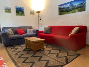 a living room with a red couch and a table at SPINALE casa in centro, arrivi con gli sci! SANIFICAZIONE A VAPORE in Madonna di Campiglio
