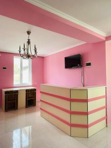 Habitación con paredes rosas y TV en la pared. en LaoVardi Hostel en Gori
