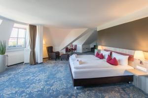 ein Hotelzimmer mit einem großen Bett mit roten Kissen in der Unterkunft martas Hotel Lutherstadt Wittenberg in Lutherstadt Wittenberg