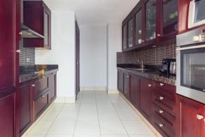 a kitchen with wooden cabinets and a white tile floor at Frank Porter - Reehan 5 in Dubai