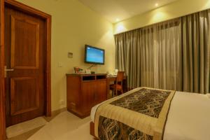 Pokój hotelowy z łóżkiem, biurkiem i telewizorem w obiekcie Resort De Coracao - Calangute , Goa w mieście Calangute