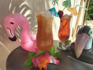 a table with two cocktails and a pink flamingo drink at Ile des Plaisirs - Domaine de Charme et table d'hôtes Caraïbéenne in Graulhet