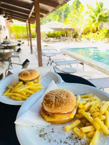 two plates of food with hamburgers and french fries on a table at Âncoradouro Hotel in Tamandaré