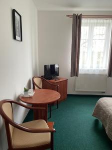 a room with a table and a bed and a television at Hotel Karolina in Karlovy Vary