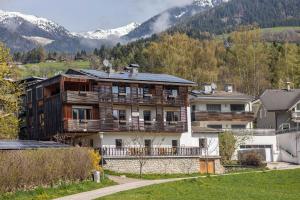 una casa grande en un pueblo con montañas en el fondo en Silbernagl Terrasse - Blick zum See, en Issengo