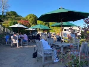 een groep mensen die aan tafels onder parasols zitten bij The Globe Inn in Kingsbridge