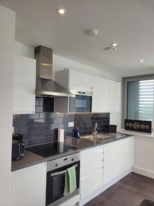a kitchen with white cabinets and a sink at Brand new apartment 20 mins from London Waterloo BP34 in London