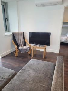 a living room with a tv and a chair and a table at Brand new apartment 20 mins from London Waterloo BP34 in London