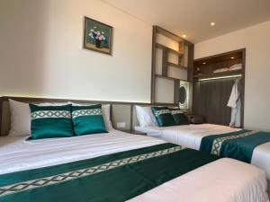 two beds in a room with green and white at Apec Mandala Chambay Mũi Né - M1820 in Ấp Long Sơn