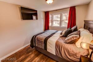 Cette chambre comprend un lit avec des rideaux rouges et une télévision. dans l'établissement *H* NEW! Manitou Springs Downtown Retreat *, à Manitou Springs