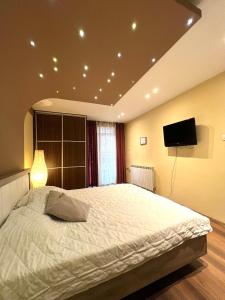 a bedroom with a large bed with a flat screen tv at Reina Apartments Skopje 3 in Skopje