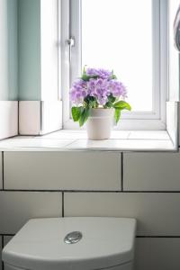 a vase of flowers sitting on a window sill at Luxurious 2-Bed House in Dartford in Dartford +12 photos