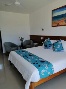 a bedroom with a large bed with blue pillows at Casa los Vientos de Vichayito in Los Órganos