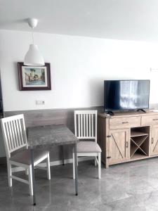 a dining room table with two chairs and a tv at Relax apartamento 5 in Las Palmas de Gran Canaria
