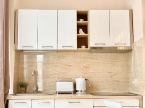 eine Küche mit weißen Schränken und einer Arbeitsplatte in der Unterkunft Super Central Chic Studio-free coffee, self check in & check out in Oradea