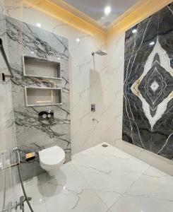 a bathroom with a toilet and a marble wall at Hotel Sky Wood At Airport in New Delhi