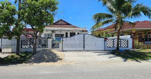 a white fence in front of a house with palm trees at Beril Homestay Full Aircond, Free Wifi, Netflix, Water Filter in Paka