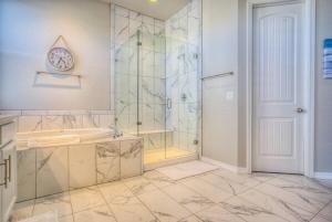 a bathroom with a shower and a clock on the wall at Luxury Lake House With Mountain Views & Hot Tub in Monument +65 photos