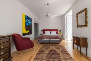 a bedroom with a bed and a red chair at Tesouro da Baixa by Shiadu in Lisbon