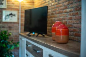 two red vases sitting on a counter with a television at Villa Selina Llanes – Terraza, Vista y Playa Cerca in La Pereda de Llanes
