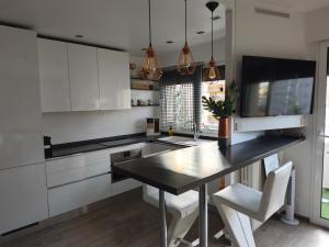 uma cozinha com armários brancos e uma mesa preta em Au jardin suspendu em Vanves