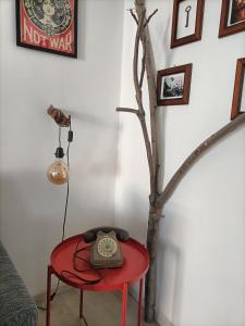 uma mesa vermelha com um relógio ao lado de uma árvore em Maison 61 em Catânia