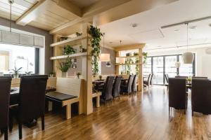 a dining room with black chairs and tables and plants at Hotel Sonne29 in Ebermannstadt