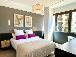 a bedroom with a large bed with purple pillows at Feelathome Nervión Apartments in Seville