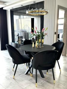 a dining room table with black chairs and a chandelier at Apartamenty Blue Baltic Chłopy nad morzem in Chłopy