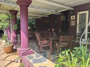 a patio with a wooden table and chairs at Pebble Fountain Guesthouse in Pretoria