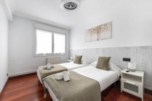 two beds in a room with white walls and wood floors at Portu Style by Aston Rentals in Portugalete