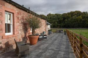 a brick building with chairs and a potted tree on a patio at The Bothy at Dryburgh in Saint Boswells