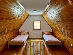 two beds in a room with wooden walls at Holiday Home Krajina II in Vlasic