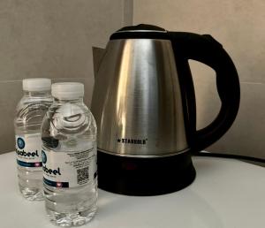 a tea kettle and two bottles of water on a counter at Cozy Apartment in Boshar in Muscat