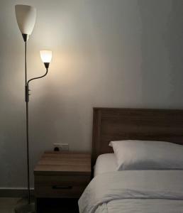 a bedroom with a bed with a lamp and a night stand at Cozy Apartment in Boshar in Muscat