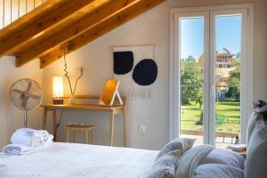 a bedroom with a bed and a desk and a window at The Hidden Attique in Corfu