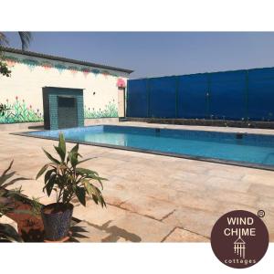 a swimming pool in front of a building at Windchime Cottages in Alibaug