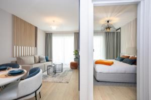a living room with a white couch and a room with a table at Baltic Waves Resort by PI Apartments - Official Operator in Międzyzdroje