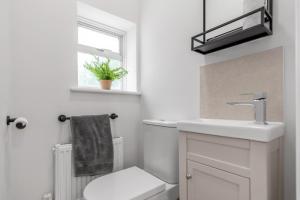 a bathroom with a toilet and a sink and a window at Coastal 6-bed with hot tub in Cromer +28 photos