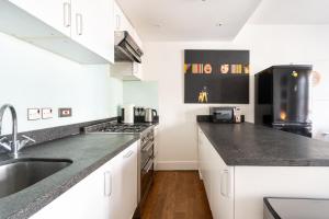 a kitchen with white cabinets and black counter tops at Notting Hill, Portobello, Kensington Chelsea in London