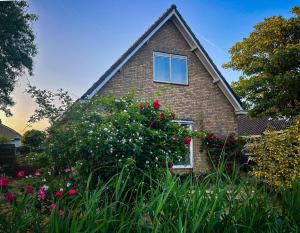 a brick house with a window and some flowers at Bed and Relax Terschelling in Midsland